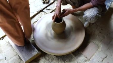 Bir kadın çömlekçinin yakın plan çekimi ayağıyla bir tekerleği döndürür ve eski şehir Hoi An, Vietnam 'da çömlek imalatında elleriyle güzel bir çömlek yapar.