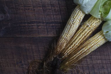 Raw sweet corn on brown wooden table. Top view, close up, copy space . Healthy food concept