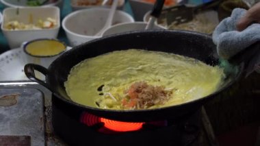 Cook Tayland 'da Bangkok' ta bir gece marketinde Tayland omleti hazırlıyor. Tayland sokak yemeği. Tayland geleneksel mutfağı. Tofu peynirli omlet, yumurta, soya fasulyesi filizi ve sebze, yakın plan.