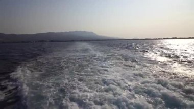 Hızlı yat teknesiyle mavi okyanus suyu dalgası pervane yıkama köpüğünü uyandırıyor. Geminin hareketi sırasında su damlaları sıçrıyor. Seyahat ve doğa kavramı