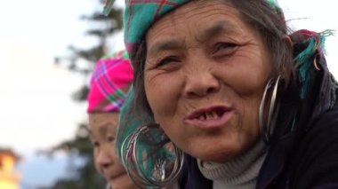 Sapa, Vietnam - Mart 06, 2020: Geleneksel kıyafet ve mücevher giyen etnik Hmong kadını turistlerin Sapa, Kuzey Vietnam 'daki dağ köyünde el sanatları satmalarını bekliyor