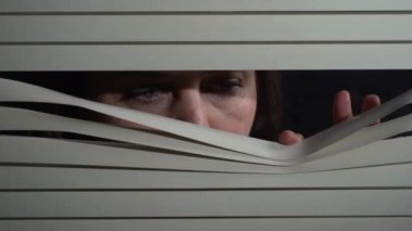 Kapalı alandaki esmer kadının pencereye elleriyle panjur iterken çekilmiş ön portresini kapat. Dışarıdan korkunç görünüyor.