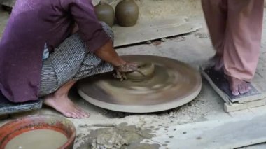 Close-up of a woman potters rotate a wheel with her foot and making a beautiful clay pot with her hands at pottery manufacture in the Old Town Hoi An, Vietnam