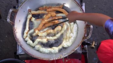 Malaysian man cooking traditional dessert food in a large pan in hot oil on night street market at Kota Kinabalu, Malaysia, close up