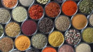 Arka planda yemek pişirmek için çeşitli aromatik baharatlar, tohumlar ve kuru otlar. Smal cam kaselerde dönüyorlar, kapatıyorlar, üstten bakıyorlar.