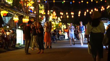 Hoi An, Vietnam - 15 Mart 2020: Avrupalı turistler eski Hoi An şehrinin merkezindeki restoranların yanında nehir boyunca yürüyorlar.