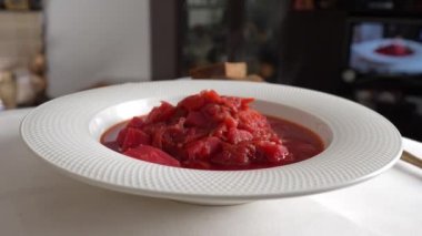 Geleneksel Ukrayna kırmızı çorbası veya kırmızı pancar, patates, havuç, lahana, beyaz kasede fasulye, yakın çekim. Bir tabak kırmızı pancar çorbası çorbası masada döner. Geleneksel Ukrayna yemekleri