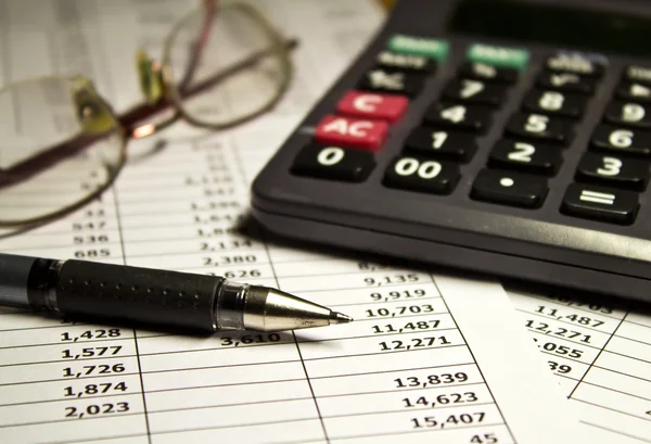 Bril, rekenmachine en pen op papier — Stockfoto