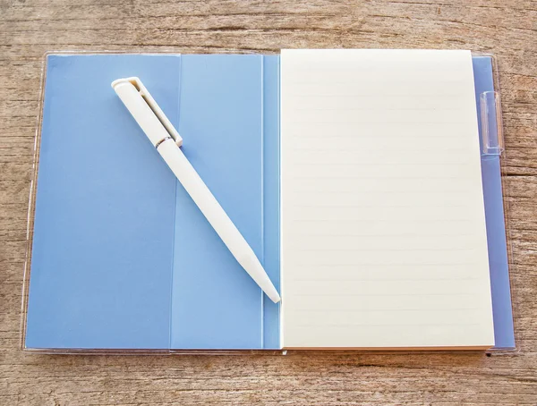 Un carnet ouvert et un stylo blanc sur fond bois — Photo