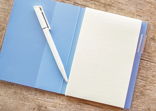 An open notebook and white pen on wood background — Stock Photo, Image