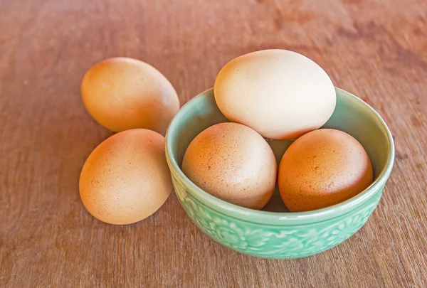 Huevos en tazón rústico sobre una mesa de madera — Foto de Stock