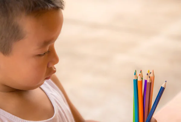 Closeup portret van een kleine jongen kijken een kleurrijke potloden — Stockfoto