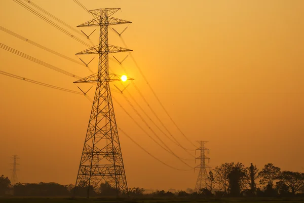 Postes eléctricos altos en la puesta del sol — Foto de Stock
