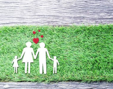 Çimlerin üzerinde kırmızı kalpli bir ailenin kağıt kesimiyle en iyi manzara. Tasarımınız için alanı kopyalayın.