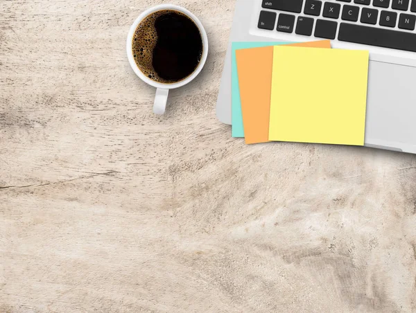 Office desk with sticky note,laptop computer,pen and cup of coffee on brown wood table background. Top view with copy space for text or any design.