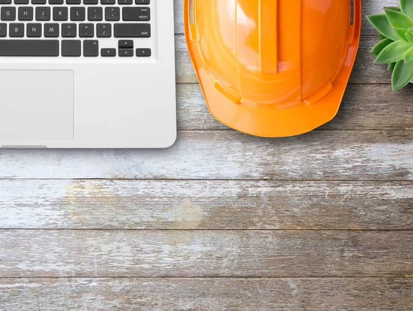 Top view with orange safety helmet and laptop computer on wood table background. copy space for design.