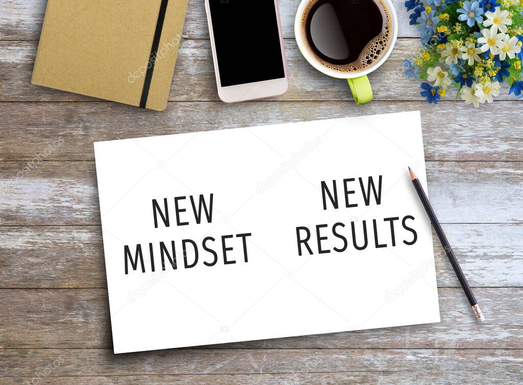 New mindset and new results text on paper on wooden table with coffee cup and smartphone Business concept of positive thinking and motivation. Flat lay with blank copy space top view.