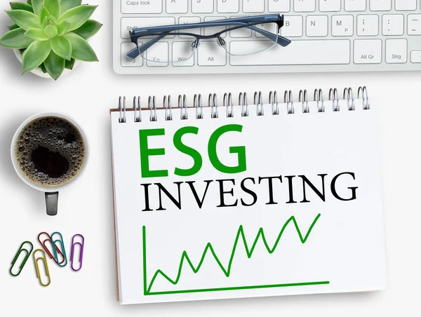 ESG investing results sign on notebook with keyboard and coffee,smartphone,glasses on office desk. Top view with copy space.Business office desk desk concept.