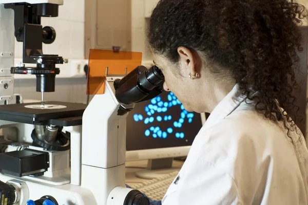 Femme scientifique regardant à travers un microscope — Photo