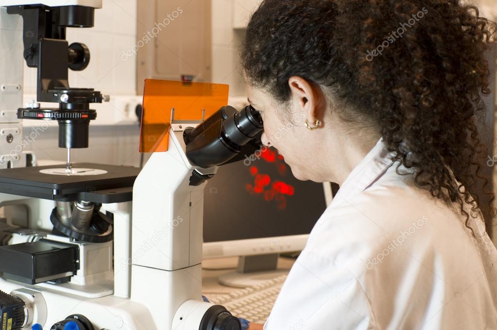 Scientist woman looking through a microscopy