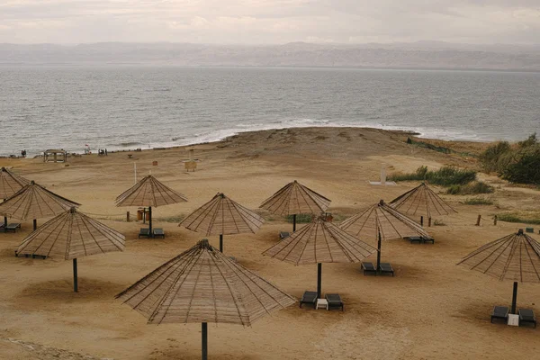 View of a beach with umbrellas on the shore of the Dead Sea from — Stock Photo, Image