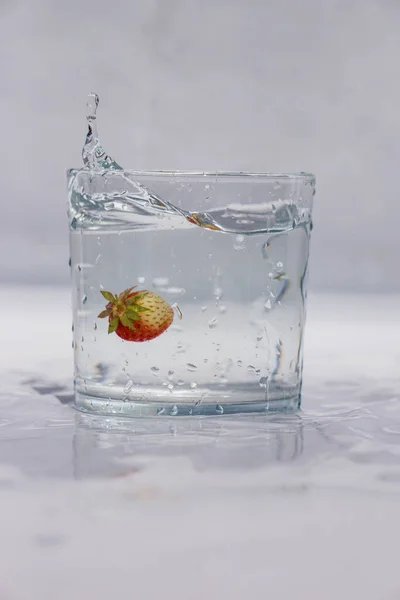 Küçük Çilek Suyla Dolu Bir Bardağa Düşüyor — Stok fotoğraf