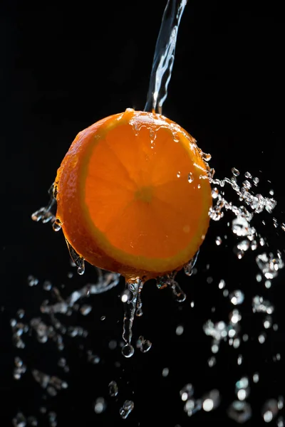 Kawałek Pomarańczy Jest Oblany Dużą Ilością Wody Czarnym Tle — Zdjęcie stockowe