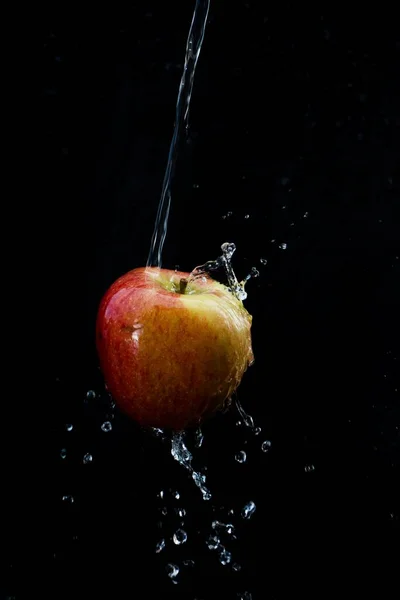 Wordt Veel Water Een Appel Gegoten Tegen Een Zwarte Achtergrond — Stockfoto