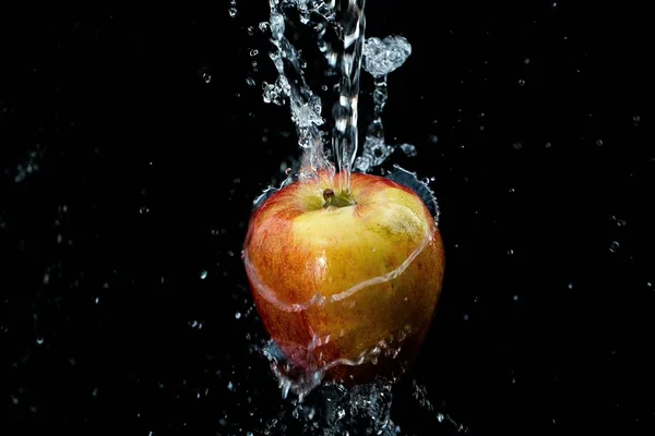 Άφθονο Νερό Χύνεται Πάνω Από Ένα Μήλο Μαύρο Φόντο — Φωτογραφία Αρχείου