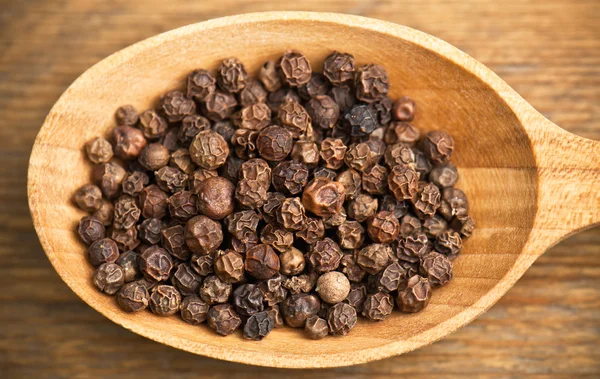 Black pepper grains in spoon — Stock Photo, Image