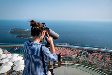 Güneşli bir günde Dubrovnik şehrinde dürbünle bakan turist kadın