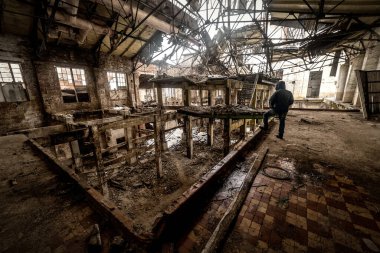Terk edilmiş ve mahvolmuş fabrikanın kalıntıları üzerinde insan kaşifi.