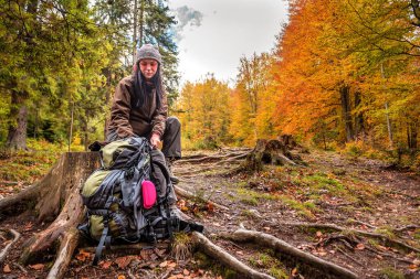 Turist kadın ormanda sırt çantasında bir şey arıyor.