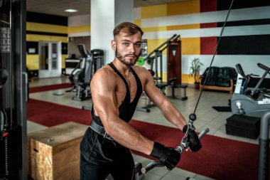 Profesyonel sporcu spor salonunda spor yapıyor, spor aletlerini kullanıyor.