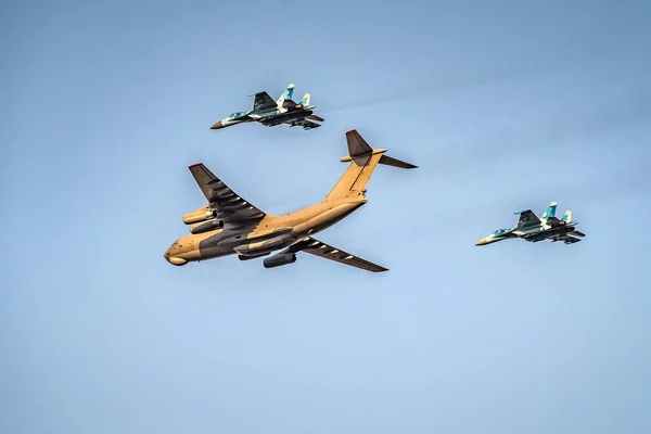 Military cargo plane escorted by two fighter planes