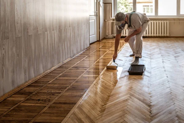 Profesional Worker Lacquering Parquet Floors Using Roller Stock Picture