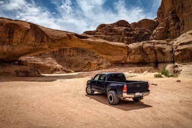 Wadi Rum Çölü 'ndeki kaya kemerinin yanındaki off-road arabası. Ürdün