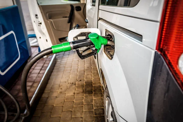 A pistol with fuel in the mouth of a gas tank at a gas station. Industrial theme