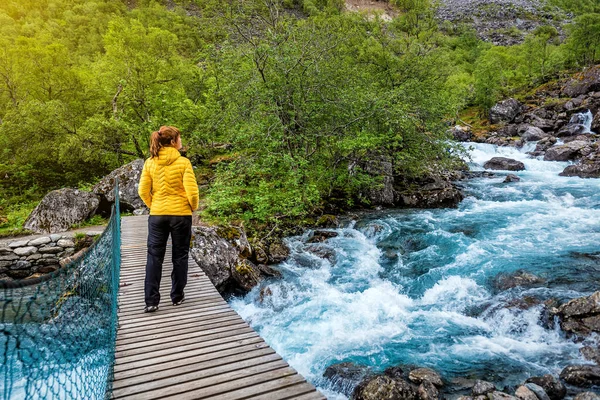 Mujer Chaqueta Amarilla Pie Puente Colgante Sobre Río Montaña Noruega — Foto de Stock