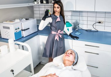 Profesyonel kozmetik uzmanı güzellik salonundaki güzel bir kadının yüzünde terapi uygular. Enjeksiyona hazır kan plazması var.