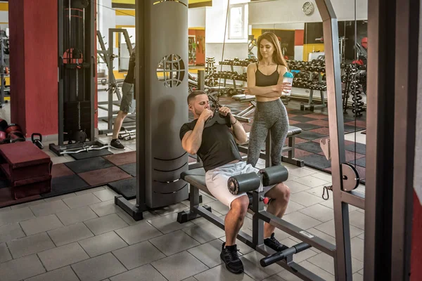 Professional trainer shows exercise to a girl in the gym