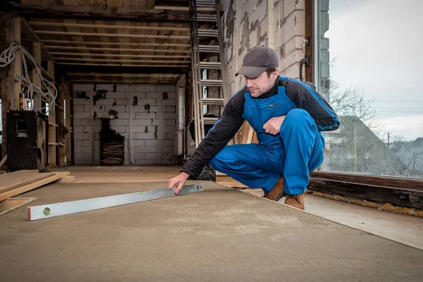 レベルツール対策コンクリート床と青全体のプロの労働者 — ストック写真