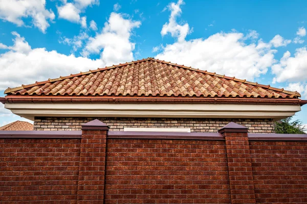 青い空の下でセラミック屋根瓦の三角形とレンガのフェンス — ストック写真