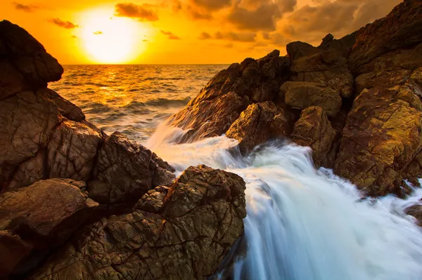 Welle plätschert im Sonnenuntergang auf den Felsen — Stockfoto