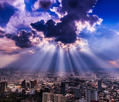 Rays of light shining through dark clouds city clipart