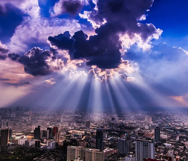 Stralen van licht schijnen door donkere wolken stad — Stockfoto