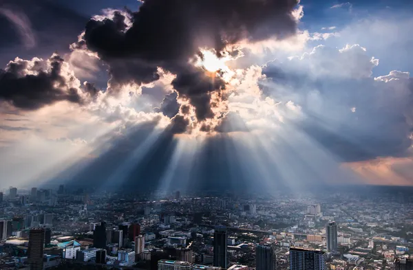 Rays of light shining through dark clouds city — Stock Photo, Image