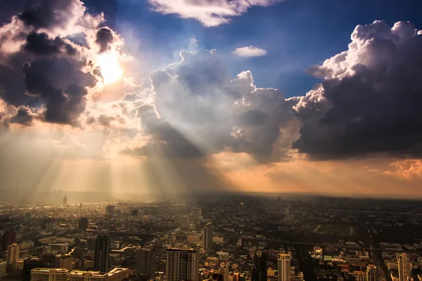 Stralen van licht schijnen door donkere wolken stad — Stockfoto