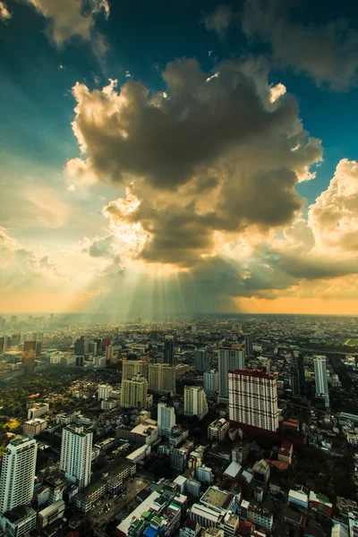 Rayos de luz brillando a través de nubes oscuras ciudad — Foto de Stock