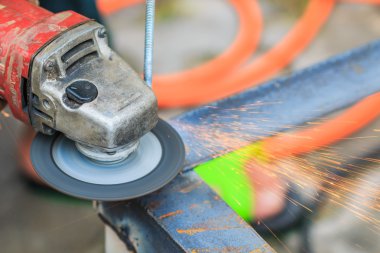 Öğütücüyle metal kesen bir işçi